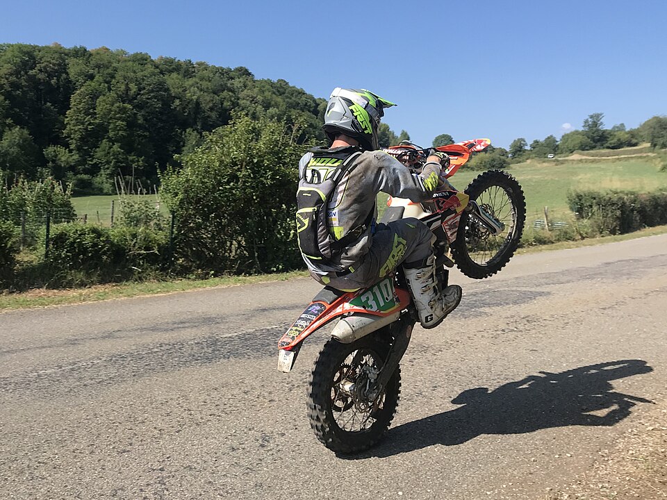 Гонщик на двухтактном KTM поднимает переднее колесо на этапе эндуро